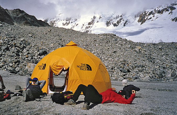 Mark Holbrook (left) and Hans Saari dozing at advanced base camp. Lowe and Bridges were killed in the large, open glaciers above, and the avalanche came down from the peaks in the clouds. [Photo] Andrew McLean